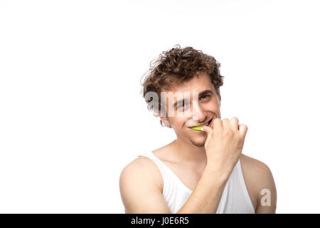 Curly divertente gli uomini con la canottiera bianca spazzolando i suoi denti con cura, isolato su bianco Foto Stock