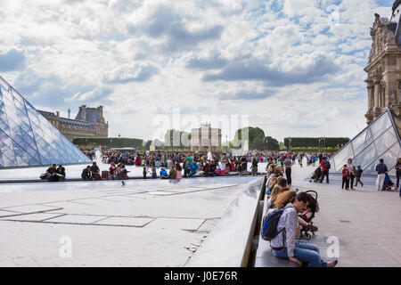 La folla seduti attorno a un giorno d'estate al Louvre, Parigi, Francia Foto Stock