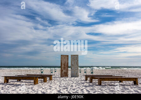 Un design concettuale con porte, panchine e lampade sulla sabbia di fronte al surf. Foto Stock