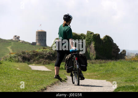 Un ciclista si ferma ad ammirare la vista a L'Ancresse scappatoia torre presso l'Ancresse baia sulla costa nord dell'isola di Guernsey nelle isole del Canale, Britai Foto Stock