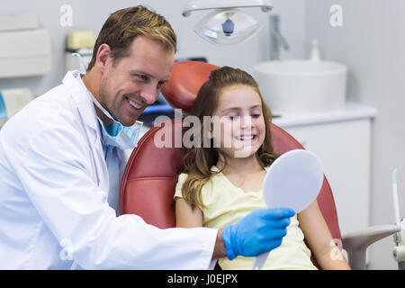 Sorridente dentista specchio mostrando alla giovane paziente in Clinica Dentale Foto Stock