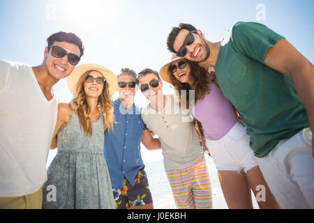 Allegro giovani amici in piedi contro il cielo durante la giornata di sole Foto Stock