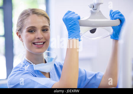 Ritratto di donna infermiera regolazione luce dentale in clinica Foto Stock