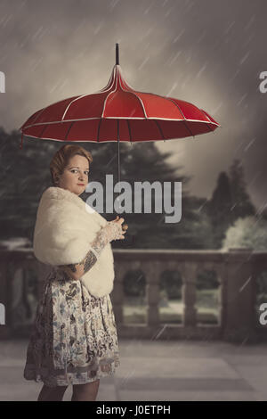 Giovane donna con ombrello in caso di pioggia Foto Stock