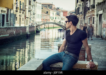 Giovane uomo su ponte sullo stretto canale di Venezia Foto Stock