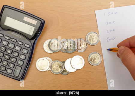 La scrittura a mano note, calcolatrice e denaro sul tavolo di legno. Foto Stock