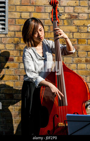 Una giovane donna musicista suonava in Brick Lane, Londra, Inghilterra Foto Stock