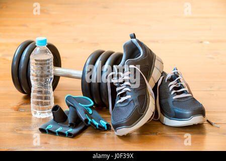 Uomini sneakers e un manubrio sul pavimento nella palestra di close-up Foto Stock