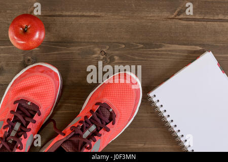 Scarpe da donna e un notebook per la registrazione dei risultati sportivi sul pavimento in legno Foto Stock