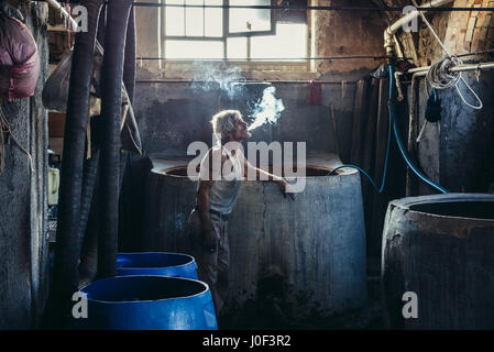 Lavoratore iraniano cigartette fumo in lana di piccola casa di colorante sul vecchio bazar di Kashan città, capitale della contea di Kashan in Iran Foto Stock