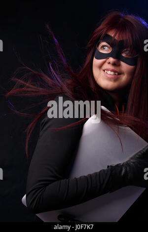Donna con capelli lunghi in maschera detiene il computer portatile Foto Stock