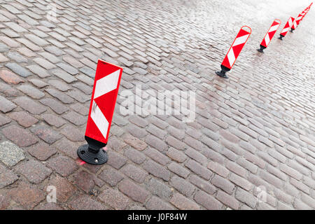 Verticali di colore rosso e bianco striato attenzione cartelli stradali stand in una fila di dividere un area di parcheggio Foto Stock