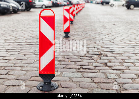 Rossa e bianca a strisce attenzione cartelli stradali stand in una fila di dividere un area parcheggio Foto Stock