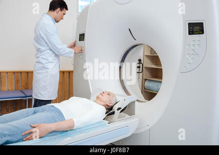 La diagnostica medica. Grave buona ricerca medico maschio premendo i pulsanti sul pannello di controllo e facendo la diagnostica medica mentre usando scanner MRI Foto Stock