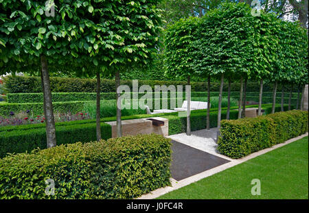 Un classico giardino con un viale di yew, box e carpino portando ad una funzione di acqua e la scultura Foto Stock