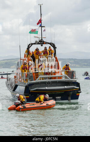 RNLI scialuppa di salvataggio con un equipaggio completo lanciando un rigido inflateable barca o costola costiera imbarcazioni di salvataggio al largo della costa di Anglesey North Wales Foto Stock