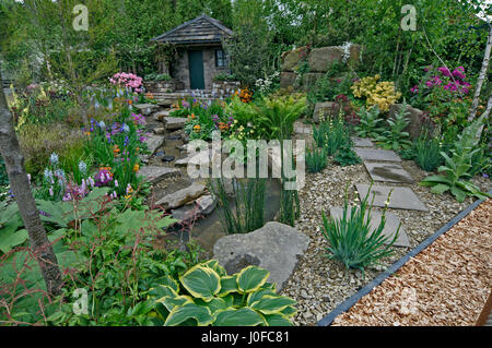 Un paese Garden cottage in una boscosa rockery con colorati piantagione Foto Stock