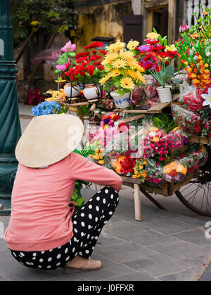 Ritratto verticale di una signora che vendono fiori dalla parte posteriore di una bicicletta in Hoi An, Vietnam. Foto Stock