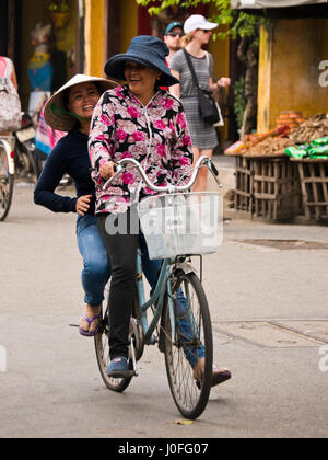 Ritratto verticale del signore di andare in bicicletta attraverso le strade di Hoi An, Vietnam. Foto Stock