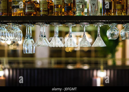 Fila di vari bicchieri da cocktail appeso a testa in giù in un Ristorante Bar Foto Stock