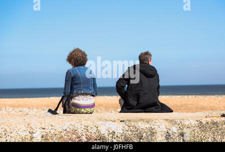 Triste premuto giovane seduta indietro per ogni altro sulla spiaggia al mare. Ful orizzontale il telaio raccolto con profondità di profonda Foto Stock
