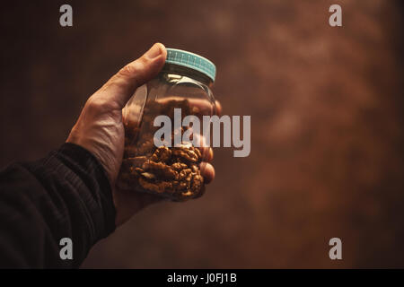 Primo piano sul vaso con le noci, tenuto in mano da un uomo. Foto Stock