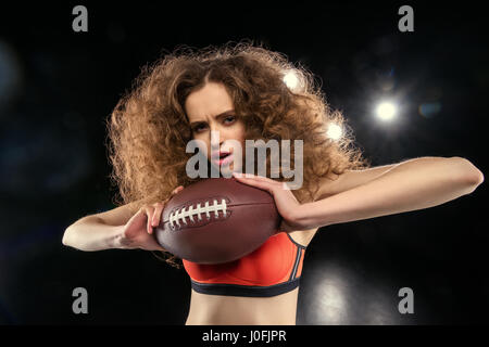 Attraente giovani sportive con capelli culry tenendo palla da rugby Foto Stock