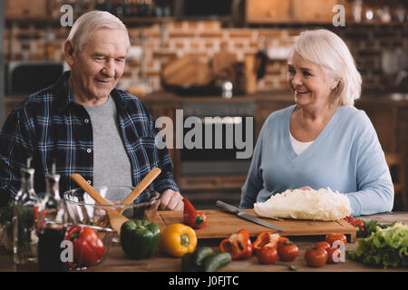 Ritratto di Allegro coppia senior in appoggio mentre rendendo salad at home Foto Stock