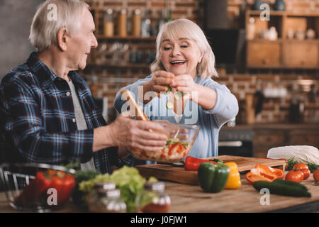 Ritratto di donna senior mettendo i cetrioli in un recipiente in marito le mani Foto Stock