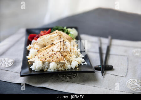 Tofu alla griglia su un letto di riso con le verdure e i bastoncini. Foto Stock