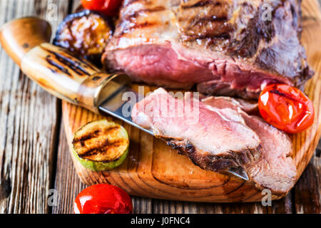 Arrosto di rare la Lombata di manzo con verdure alla griglia su rustico sfondo di legno Foto Stock
