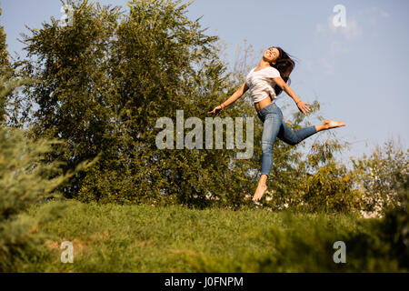 La libertà e la felicità concetto con una donna a piedi nudi saltando da qualche parte al di fuori nella natura Foto Stock