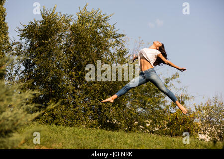 La libertà e la felicità concetto con una donna a piedi nudi saltando da qualche parte al di fuori nella natura Foto Stock