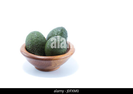 Fresco verde avocado in un legno naturale recipiente isolato in uno sfondo bianco Foto Stock