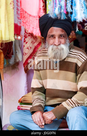 Amichevole maschio barbuto negoziante Sikh in un negozio di tessuti che indossa tipico turbante, Pragpur, un villaggio del patrimonio culturale nel quartiere Kagra, Himachal Pradesh, India Foto Stock