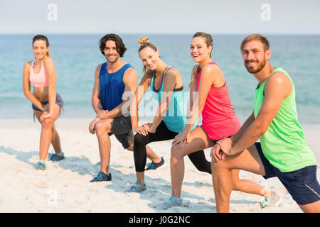 Ritratto happy amici stretching in riva al mare Foto Stock