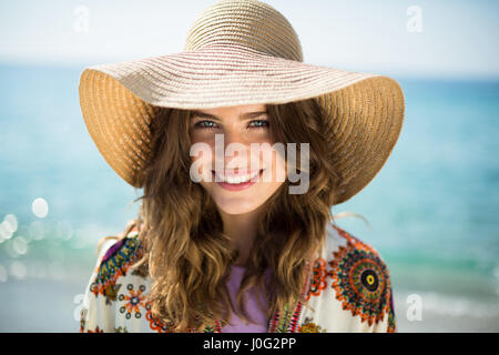 Close up ritratto di felice giovane donna indossa cappello da sole contro il mare Foto Stock