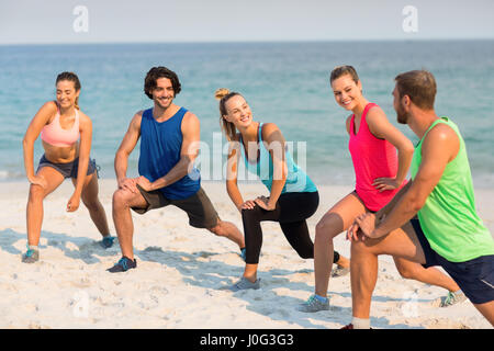 Lunghezza completa di happy amici stretching in riva al mare Foto Stock