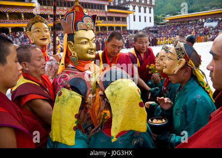 Figura mascherata essendo portato passato folla, Festival, Trashichhoe Dzong, monastero, Thimpu, Bhutan Foto Stock