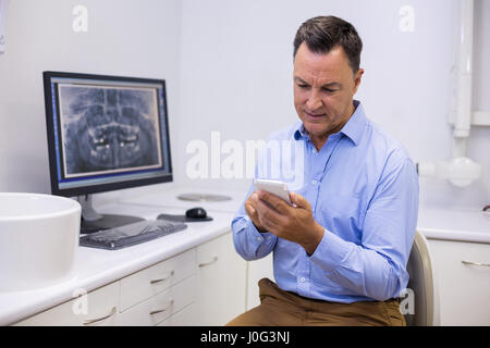 Dentista tramite telefono cellulare in clinica Foto Stock