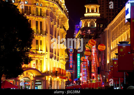 Edifici illuminata di notte con bandiere cinesi, Nanjing Road, Shanghai, Cina Foto Stock