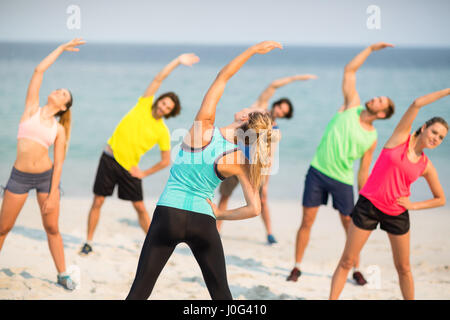 Amici stretching mentre si sta in piedi sul litorale di spiaggia Foto Stock