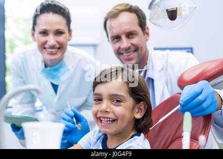 Ritratto di dentista esaminando un paziente giovane con strumenti in clinica dentale Foto Stock