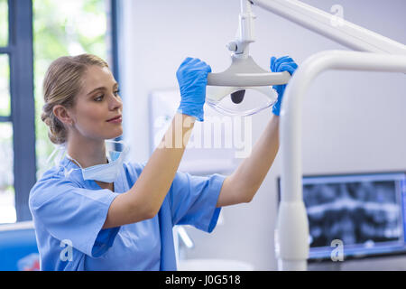 Infermiera femmina regolazione luce dentale in clinica Foto Stock