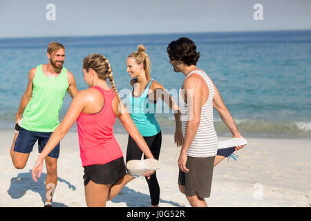 Gli amici che esercitano in spiaggia sulla giornata di sole Foto Stock