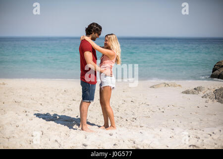 Vista laterale della coppia giovane in piedi faccia a faccia presso la spiaggia Foto Stock