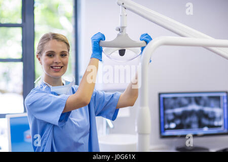 Ritratto di donna infermiera regolazione luce dentale in clinica Foto Stock