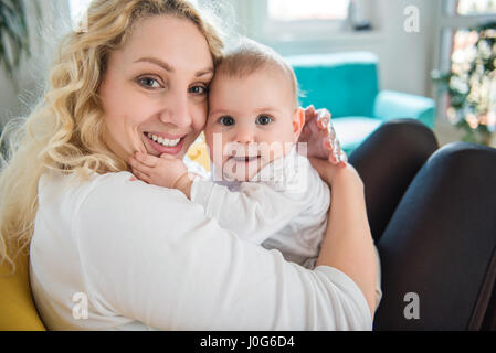 La madre tiene il Bambino fra le braccia e seduti in poltrona di colore giallo Foto Stock