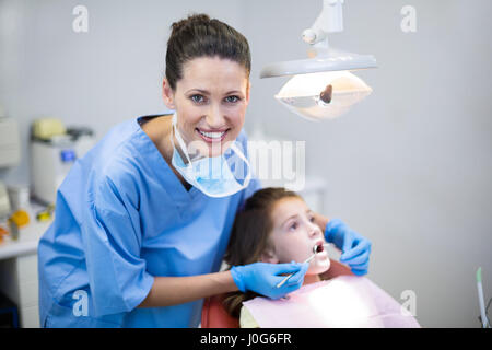 Ritratto di dentista esaminando un paziente giovane con strumenti in clinica dentale Foto Stock