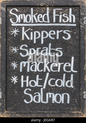 Una lavagna mostra una gamma di pesce affumicato disponibile per l'acquisto. Foto Stock